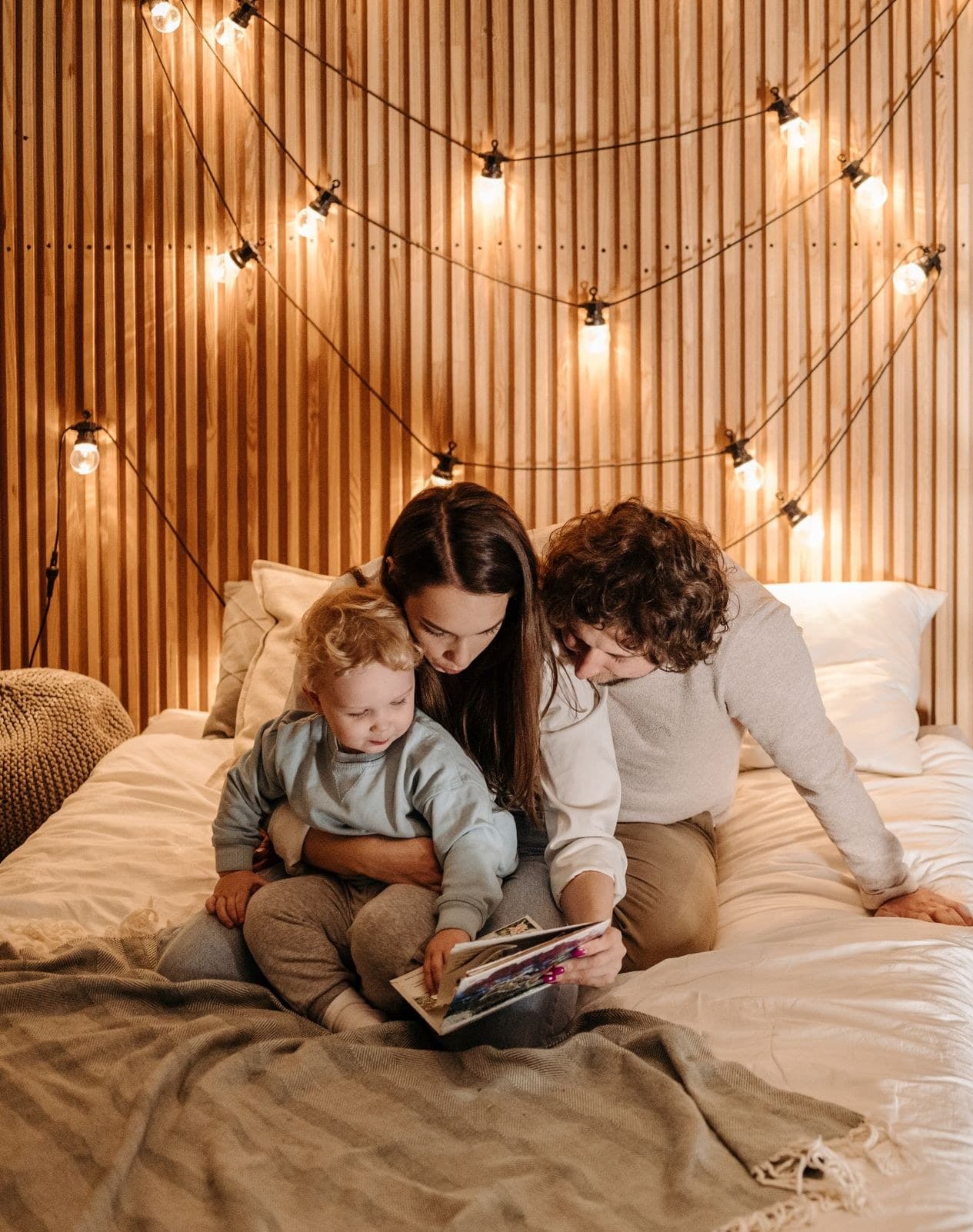 A family reading together on their bed in a warmly lit home